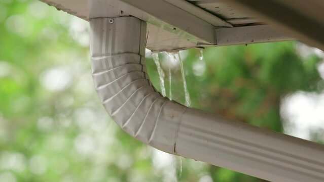 Rain Pours Off a Roof and Overflows a Rain gutter eavestrough system exceeding capacity
