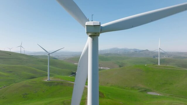 Close up aerial view of large rotating windmill turbine in green park, generating renewable energy. Environment, sustainability, green energy, climate change concept. Aerial 4K footage, nature USA