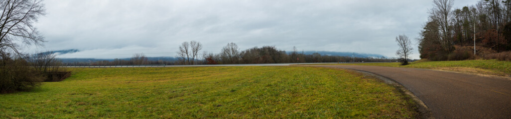 Fototapeta na wymiar Grass field with road and overcast sky