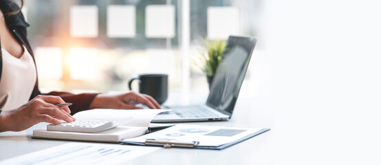 Close up Business woman hand using calculator to calculate the company's financial results and...