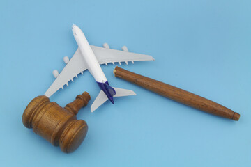 Broken judge gavel and airplane model on blue background. Flights out of laws concept.