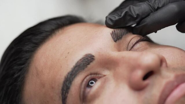 Close up shot of male microblading procedure to making permanent eyebrows makeup