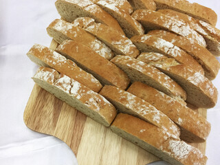 Fresh sliced baked breads on the wooden board and white silk