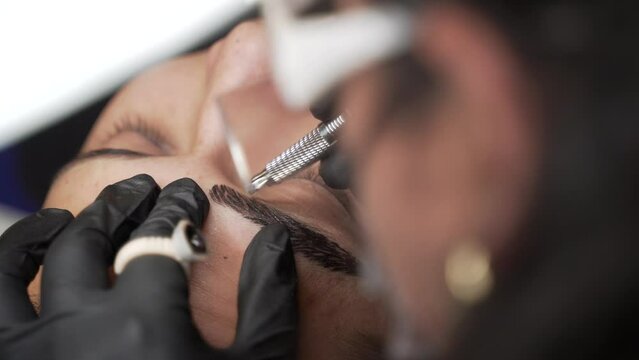 Close up shot of beautician with gloves making male eyebrow microblading procedure