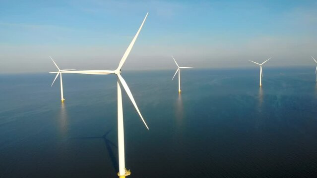 Windmill park in the ocean, drone aerial view of windmill turbines generating green energy electric, windmills isolated at sea in the Netherlands. High quality 4k footage