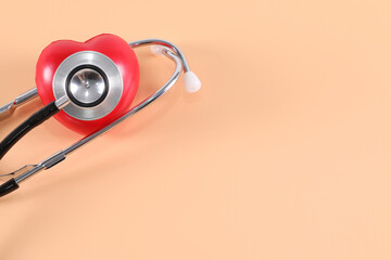 Fototapeta na wymiar Stethoscope with red heart on orange background, heart examination, medical equipment the doctor used to examine the patient have copy space.