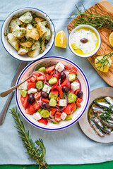 Greek food table scene, top view . Variety of items including greece salad, cucumber dip Tzatziki, Anchovy fillets, lemon potatoes.