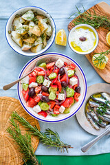 Greek food table scene, top view . Variety of items including greece salad, cucumber dip Tzatziki, Anchovy fillets, lemon potatoes.