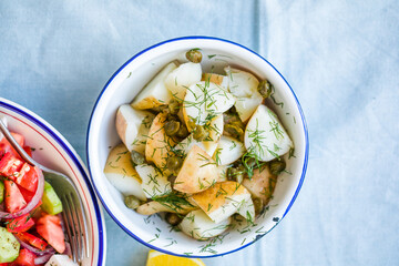 Potato salad with dill and olives in a  bowl on a blue  background.  Healthy food, vegan and lean recipes.