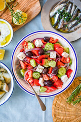 Greek food table scene, top view . Variety of items including greece salad, cucumber dip Tzatziki, Anchovy fillets, lemon potatoes.