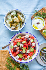 Greek food table scene, top view . Variety of items including greece salad, cucumber dip Tzatziki, Anchovy fillets, lemon potatoes.