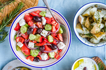 Greek food table scene, top view . Variety of items including greece salad, cucumber dip Tzatziki, Anchovy fillets, lemon potatoes.