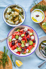 Greek food table scene, top view . Variety of items including greece salad, cucumber dip Tzatziki, Anchovy fillets, lemon potatoes.