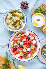 Greek food table scene, top view . Variety of items including greece salad, cucumber dip Tzatziki, Anchovy fillets, lemon potatoes.