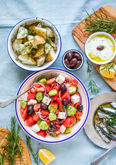 Greek food table scene, top view . Variety of items including greece salad, cucumber dip Tzatziki, Anchovy fillets, lemon potatoes.
