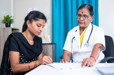 female patient signing documents in front of doctor at hospital - concept of health insurance, and...