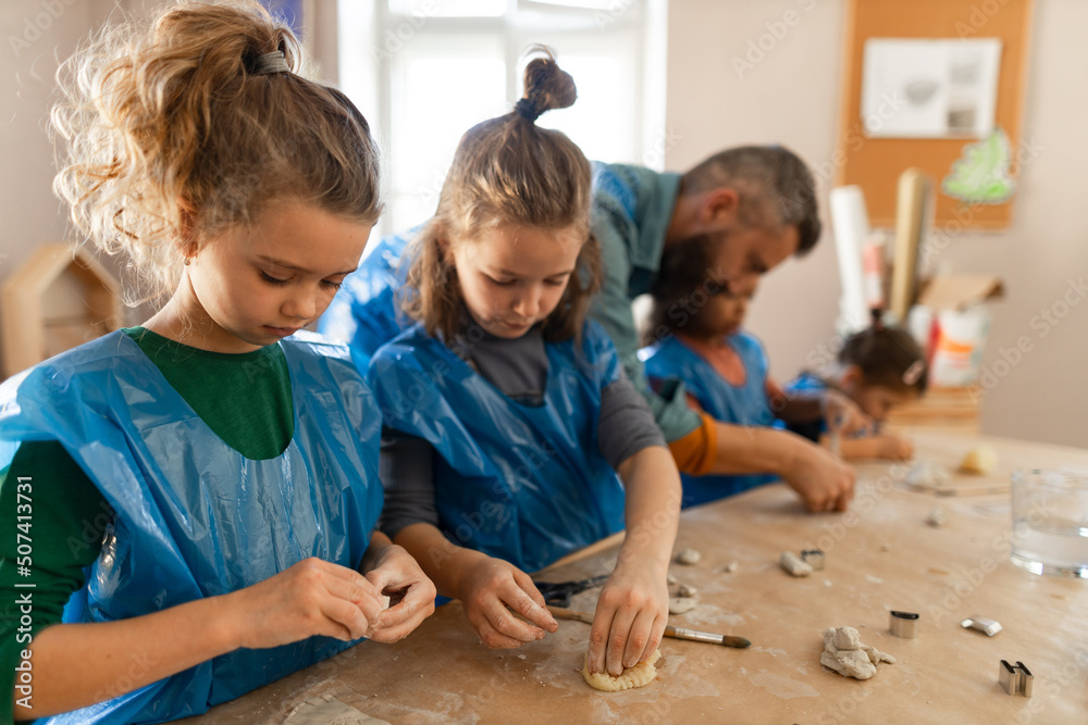 Wall mural Group of little kids with teacher working with pottery clay during creative art and craft class at school.