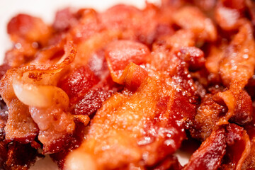 Macro view of appetizing, tasty, fried, crispy bacon slices, close-up, meat ham to scrambled eggs, shallow depth of field