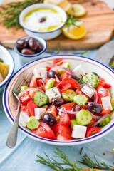 Greek salad with feta cheese, olives, cherry tomato, paprika, cucumber and red onion, healthy vegeterian mediterranean diet food, low calories eating. White stone background, top view
