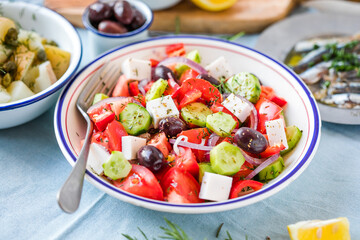 Greek salad with feta cheese, olives, cherry tomato, paprika, cucumber and red onion, healthy vegeterian mediterranean diet food, low calories eating. White stone background, top view