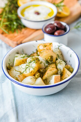 Potato salad with dill and olives in a  bowl on a blue  background.  Healthy food, vegan and lean recipes.