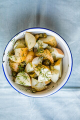 Potato salad with dill and olives in a  bowl on a blue  background.  Healthy food, vegan and lean recipes.