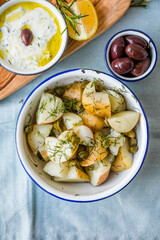 Potato salad with dill and olives in a  bowl on a blue  background.  Healthy food, vegan and lean recipes.