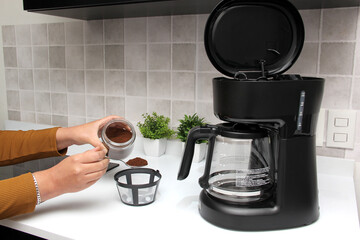 Woman's hands prepare delicious and aromatic coffee in coffee maker in the kitchen for breakfast with water and freshly ground coffee
