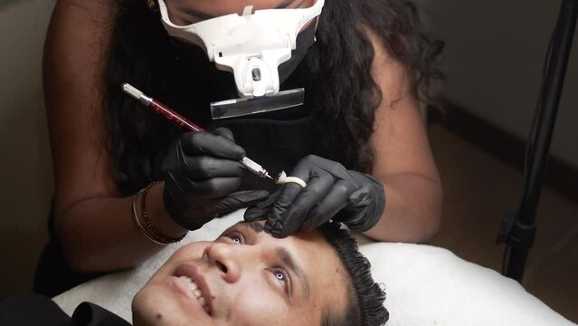 Makeup artist with gloves making microblading procedure to permanent eyebrows makeup