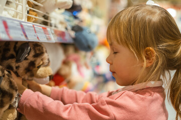 Little caucasian girl coosing a new toy in the big baby store.