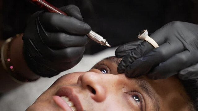 Close up shot of male microblading procedure to making permanent eyebrows makeup