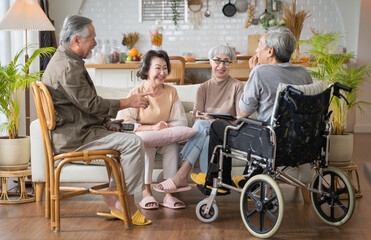 Group Asian seniors friends are sitting in the living room of a home together, enjoying talking...