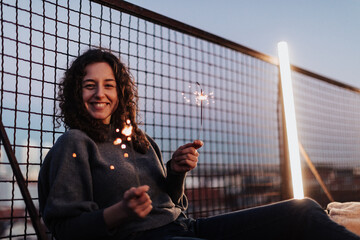 Young woman with sparklers having fun at rooftop in the city, close up.