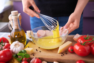 Woman beating egg yolks with a whisk making homemade pasta carbonara