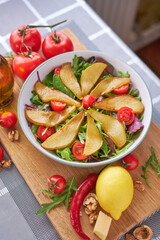 Salad with pears, tomatoes and arugula on wooden board