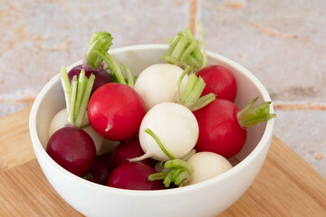 close up of tricolor radishes in a bowl on a table