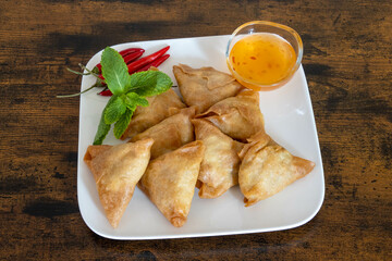 top view of samosa in a white plate with sweet and sour sauce