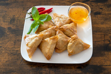 top view of samosa in a white plate with sweet and sour sauce
