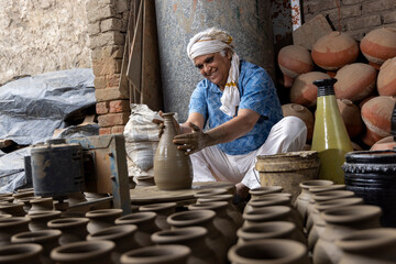 Skilled hands of a potter shaping the clay into pot on spinning wheel