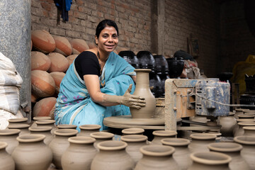 Skilled hands of a female potter shaping the clay into pot on spinning wheel
