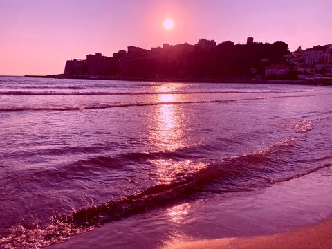 Purple pink sunset over the sea at the beach. Glittering sea waves at evening.