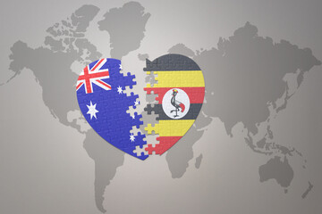 puzzle heart with the national flag of uganda and australia on a world map background. Concept.