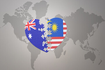 puzzle heart with the national flag of malaysia and australia on a world map background. Concept.