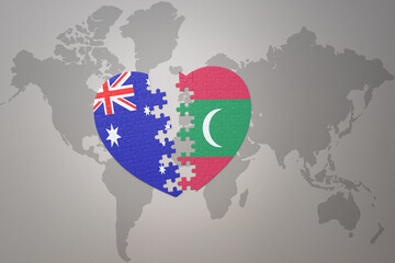 puzzle heart with the national flag of maldives and australia on a world map background. Concept.