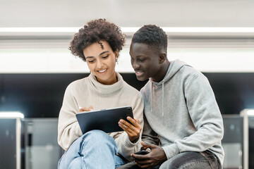 couple of students using digital sitting in the subway.