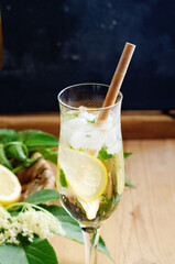 Fresh summer eldenflower drink HUGO with lemon and mint on rustic wooden background.
