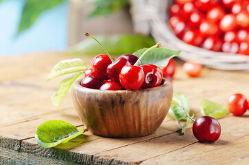 Organic fresh cherries in a wooden bowl on rustic wooden background. 