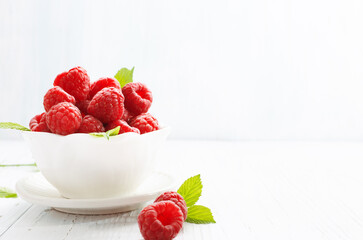 Fresh raspberry in a white bowl on a white background.