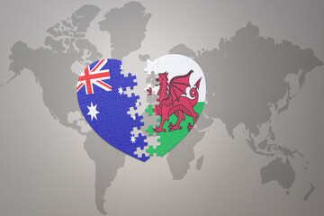 puzzle heart with the national flag of wales and australia on a world map background. Concept.