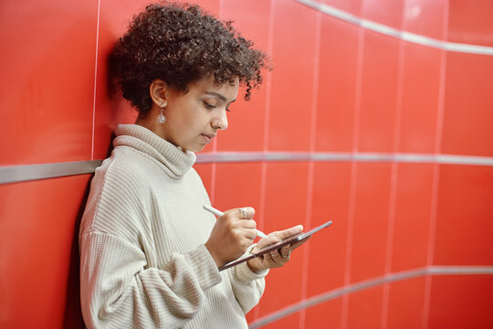 young woman with a digital tablet standing near the wall in the subway .
